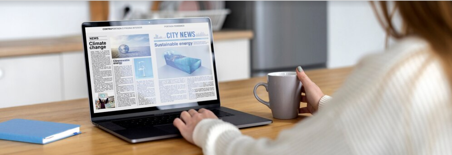 Women reading news on her laptop sitting on a table.